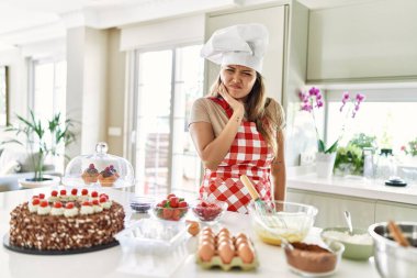 Güzel, genç, esmer pasta şefi kadın diş ağrısı ya da diş ağrısı yüzünden mutfakta hamur işleri pişiriyor. dişçi 