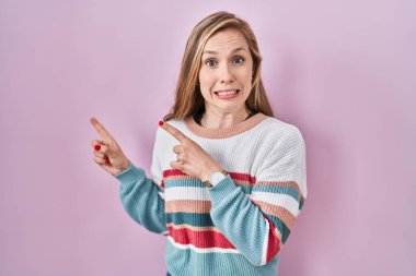 Pembe arka planda duran genç sarışın kadın endişeli ve gergin olduğunu gösteriyor. Endişeli ve şaşırmış bir ifadeyle. 