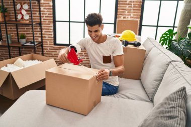 Genç İspanyol adam yeni evinde kendine güvenen bir karton kutu paketliyor.