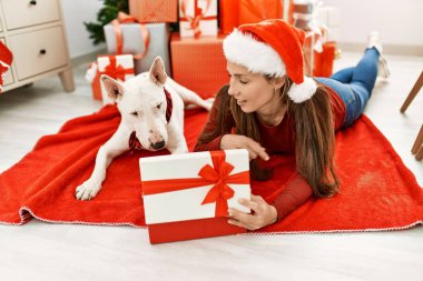 Genç Kafkas kadın boks hediyesini açıyor. Evde yılbaşı ağacının yanında köpekle yatıyor.