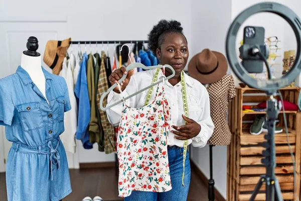 Young african american woman shopkeeper selling clothes online at clothing store