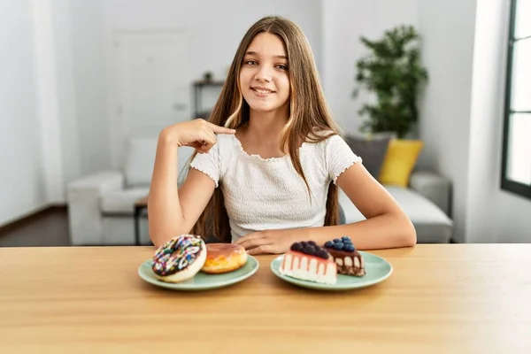 Young Brunette Teenager Eating Cakes Sweets Pointing Finger One Self — Stockfoto