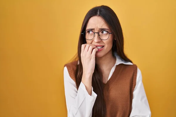 Jovem Morena Sobre Fundo Amarelo Usando Óculos Olhando Estressado Nervoso — Fotografia de Stock