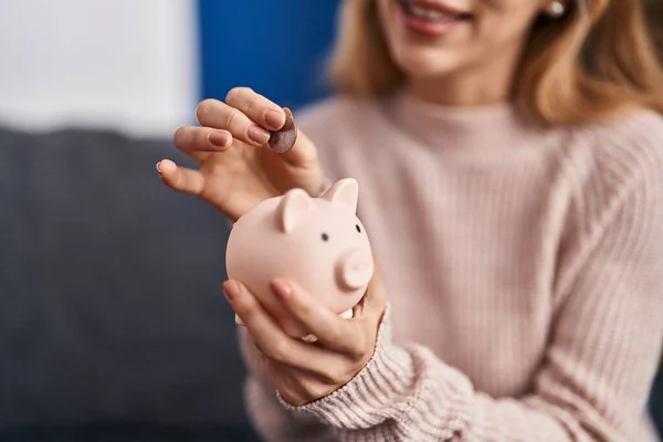 Young Woman Inserting Coin Piggy Bank Home — 图库照片