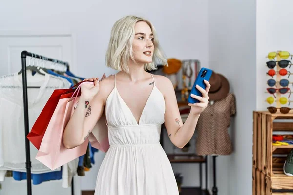 Mladá Běloška Drží Nákupní Tašky Pomocí Smartphonu Obchodě Oblečením — Stock fotografie