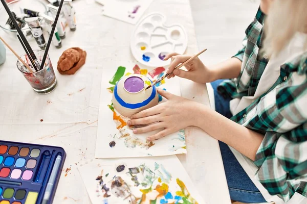 Artist student girl painting pottery at art studio.