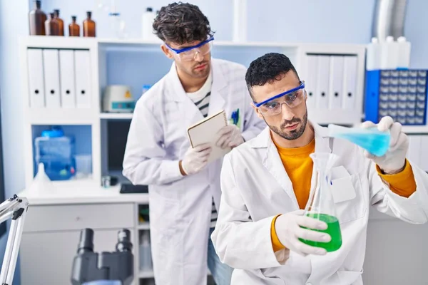 Laboratuvarda sıvıyı ölçen iki bilim adamı.