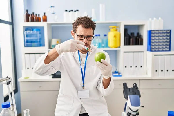 研究室でアップルに液体を注入する若いヒスパニック系の男性科学者 — ストック写真