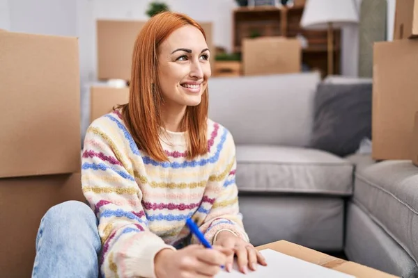 Jonge Kaukasische Vrouw Glimlachen Zelfverzekerd Schrijven Notebook Nieuw Huis — Stockfoto