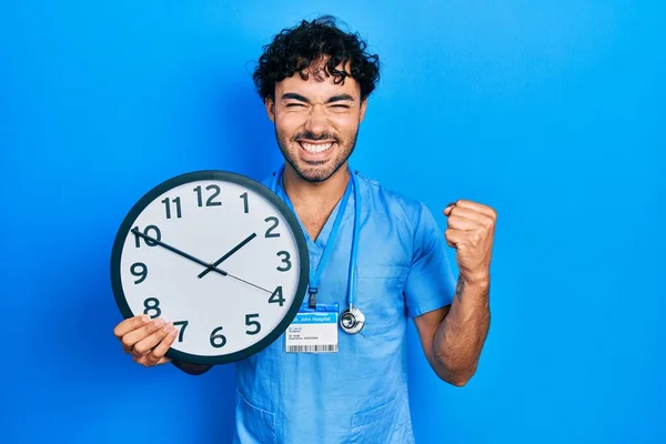 Jovem Hispânico Vestindo Uniforme Enfermeira Azul Masculino Segurando Relógio Gritando — Fotografia de Stock