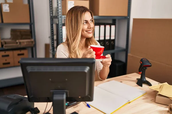Young blonde woman ecommerce business worker drinking coffee at office