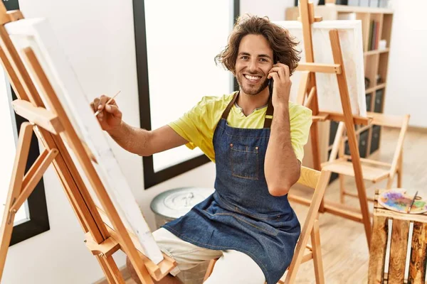 年轻的他的惊慌失措的艺术家脸上挂着快乐的图画 在艺术工作室用智能手机交谈 — 图库照片