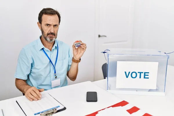 Мужчина Среднего Возраста Бородой Сидит Избирательного Бюллетеня Держа Голосую Значок — стоковое фото