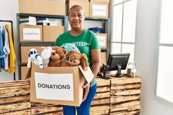 Senior African American Woman Wearing Volunteer Uniform Holding Toys Donations — Stock Photo, Image