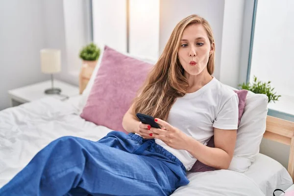 Mujer Rubia Joven Usando Smartphone Cama Haciendo Cara Pez Con — Foto de Stock