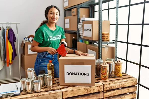 Gönüllü Üniformalı Genç Latin Kadın Yardım Merkezinde Bağış Kutusu Paketliyor — Stok fotoğraf