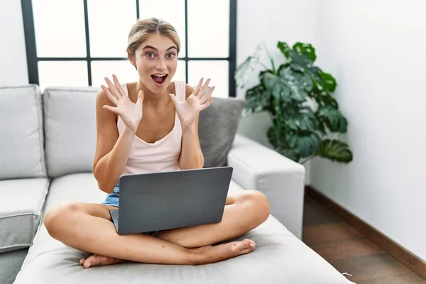 Jovem Loira Usando Laptop Casa Sentado Sofá Comemorando Louco Surpreso — Fotografia de Stock