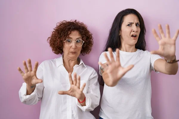 ヒスパニック系の母親と娘ピンクの背景の上にカジュアルな白いTシャツを着て恐れていると手で恐怖の表現を停止ジェスチャーを恐れて ショックで叫んでいる パニックの概念 — ストック写真