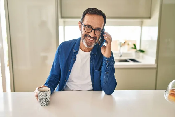 Orta Yaşlı Bir Adam Akıllı Telefondan Konuşuyor Evde Kahve Içiyor — Stok fotoğraf