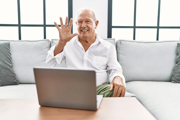Старший Чоловік Використовує Ноутбук Вдома Сидячи Дивані Показуючи Вказуючи Пальцями — стокове фото