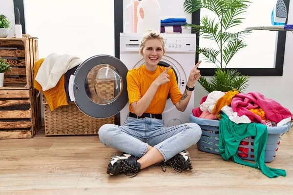 Çamaşır Makinesinin Yanında Oturan Gülümseyen Kameraya Bakan Genç Sarışın Kadın — Stok fotoğraf