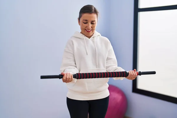 Middle age woman smiling confident training using bar at sport center