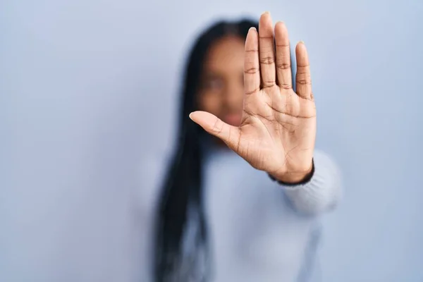 青い背景の上に立つアフリカ系アメリカ人の女性は手の手のひらで歌うのをやめます 顔に負の重大なジェスチャーで — ストック写真