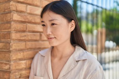 Çinli kadın gülümseyerek caddenin kenarına bakıyor.