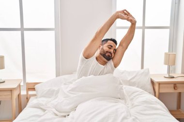 Genç İspanyol adam yatak odasında kollarını uzatıyor.