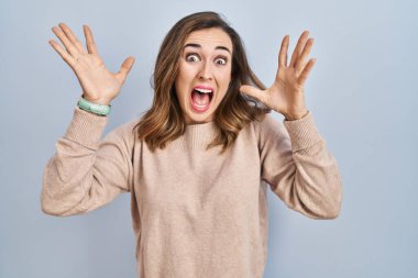 Young woman standing over isolated background celebrating crazy and amazed for success with arms raised and open eyes screaming excited. winner concept 