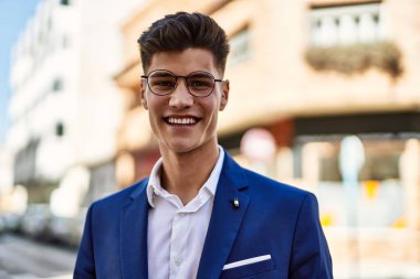 Sokakta kendine güvenen takım elbiseli ve gözlüklü bir genç.