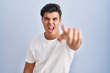 Mavi arka planda dikilen İspanyol adam kameraya kızgın ve sinirli olduğunu gösteriyor. 