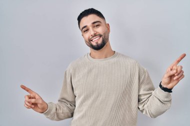 İzole edilmiş arka planda duran yakışıklı genç adam farklı yönleri gösteren kendine güvenle gülümsüyor. reklam için kopyalama alanı 