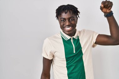 Münzevi arka planda dikilen Afrikalı adam mutlu ve neşeli dans ediyor, hareketli ve kendinden emin bir şekilde müzik dinliyor. 