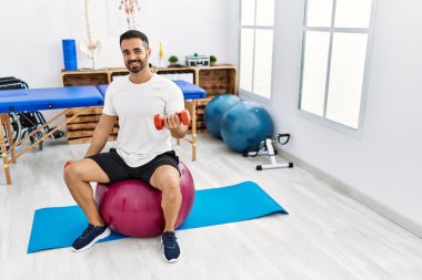 Genç İspanyol hasta, rehabilitasyon seansında sağlıklı top ve dambıllarla gülümsüyor.