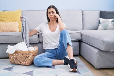 Young brunette woman doing laundry at home skeptic and nervous, frowning upset because of problem. negative person. 