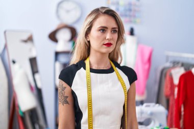 Young beautiful hispanic woman tailor standing with serious expression at clothing factory