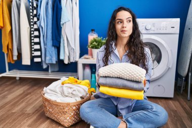 Genç esmer kadın temiz çamaşırları tutuyor. Gülümsüyor, yan tarafa bakıyor ve düşünüyor.. 