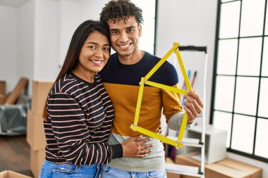 Genç latin çift gülümsüyor Mutlu ev projeleri yeni evinde tutuluyor.