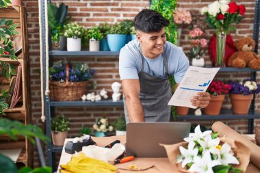 Çiçekçide dizüstü bilgisayar okuyan İspanyol bir çiçekçi.