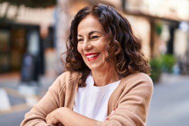 Middle age hispanic woman smiling happy with crossed arms outdoors
