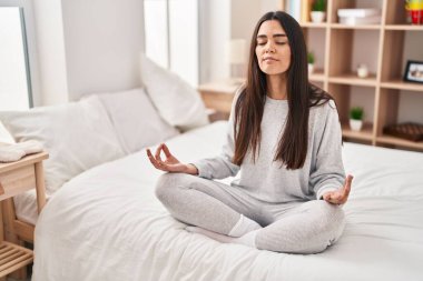 Genç İspanyol kadın yoga egzersizi yapıyor. Yatak odasında oturuyor.