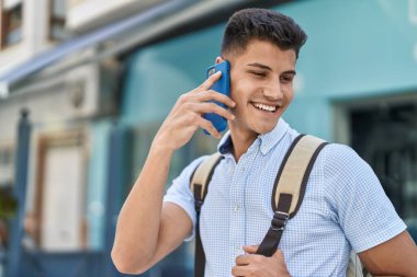 Genç İspanyol öğrenci caddede akıllı telefondan konuşuyor.