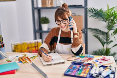 Sanat stüdyosunda akıllı telefondan resim çizen genç bir kadın sanatçı.