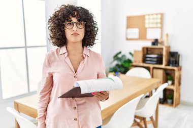 Young middle eastern woman wearing business style at office relaxed with serious expression on face. simple and natural looking at the camera. 