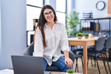 Ofiste çalışan genç İspanyol iş kadını laptopu kullanıyor.