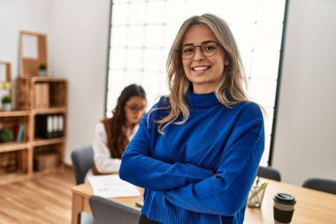 İş kadını kollarını kavuşturup mutlu bir şekilde gülümsüyor..