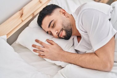Genç Arap adam yatakta uzanıyor, yatak odasında uyuyor.
