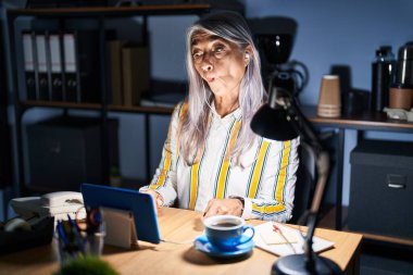 Gri saçlı, gece ofiste çalışan orta yaşlı bir kadın dudaklarıyla balık yüzü yapıyor, çılgınca ve komik bir jest. Komik ifade. 