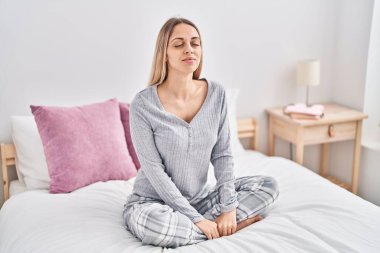 Genç bayan yatak odasında rahat bir şekilde oturuyor.